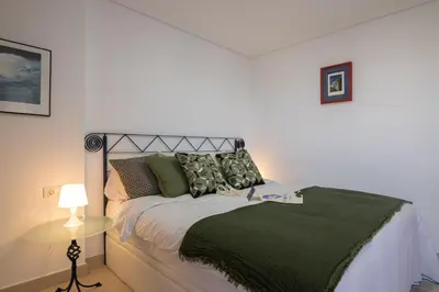 a bedroom with a bed with a green blanket at Dorm4You Patacona in Valencia
