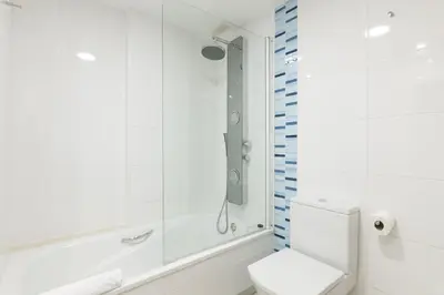a white bathroom with a shower and a toilet at Dorm4You Patacona in Valencia