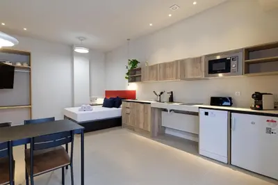 a kitchen with white cabinets and a table and a couch at Osito Hub - Colomer in Valencia