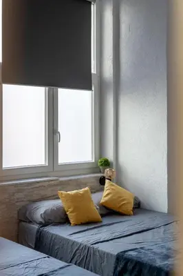 two beds with yellow pillows in a room with windows at Alojamiento, hospedaje para 6 personas in Valencia