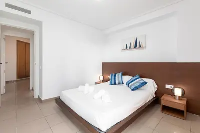 a bedroom with a large white bed with blue pillows at ApartUP Patacona Iconic II in Valencia