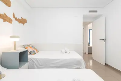 a white bedroom with two beds and a lamp at ApartUP Patacona Iconic II in Valencia