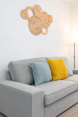 a gray couch with pillows and a clock on the wall at ApartUP Patacona Iconic II in Valencia