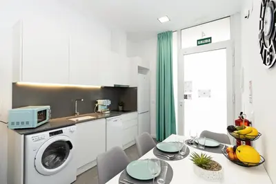 a kitchen with a washing machine and a table with chairs at GuestReady - Llovera apartments in Valencia