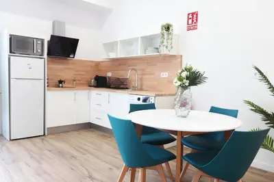 a kitchen with a white table and blue chairs at Total Valencia Sorolla in Valencia