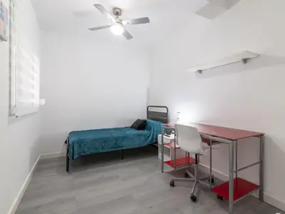 a room with a bed and a desk and a ceiling fan at Winahost Paterna Palisses in Paterna