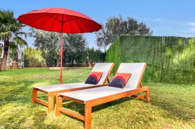 two lounge chairs with a red umbrella on the grass at Villa near Valencia 17PAX, Pool, Cinema, BBQ, KidsRoom in Manises