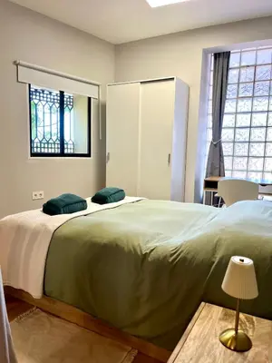a bedroom with a large bed with green sheets and a window at Encantador apartamento boutique a 5 min del metro in Bétera