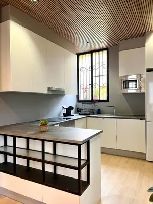 a kitchen with white cabinets and a table at Encantador apartamento boutique a 5 min del metro in Bétera