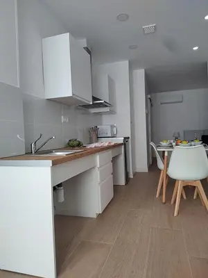 a kitchen with white cabinets and a table and a chair at New central flat with AC and Wifi in Valencia