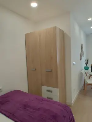 a bedroom with a large wooden cabinet and a table at New central flat with AC and Wifi in Valencia