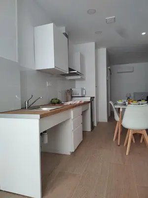 a kitchen with white cabinets and a table and chairs at New central flat with AC and Wifi in Valencia
