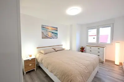 a bedroom with a bed and a dresser and two windows at El sonido del mar in Puerto de Sagunto