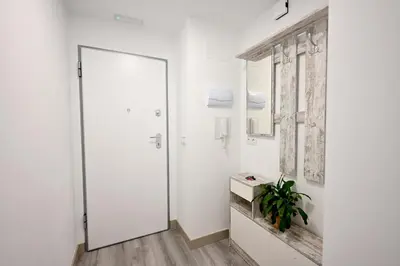 a white hallway with a door and a plant at El sonido del mar in Puerto de Sagunto