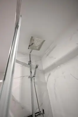 a shower in a room with white marble walls at El sonido del mar in Puerto de Sagunto