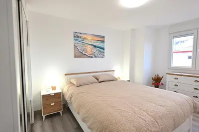 a white bedroom with a bed and a window at El sonido del mar in Puerto de Sagunto