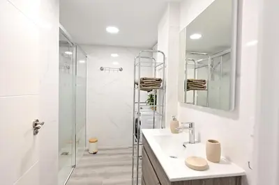 a white bathroom with a shower and a sink at El sonido del mar in Puerto de Sagunto