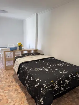 a bedroom with a bed with a black bedspread with flowers at Hogar Mediterráneo in Valencia