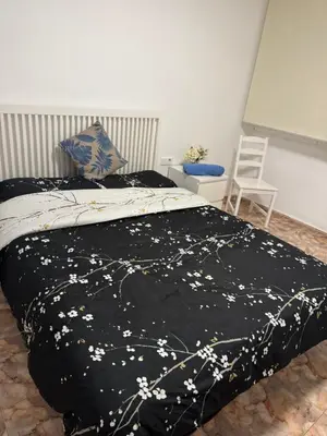 a bed with a black blanket with white flowers on it at Hogar Mediterráneo in Valencia