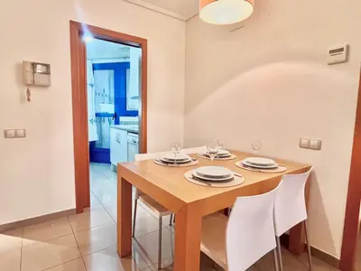 a dining room with a wooden table and white chairs at Complejo de playa in Valencia