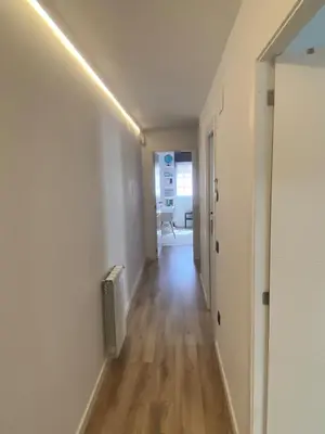 a hallway with white walls and wood floors and a light fixture at Family Home Valencia in Aldaia