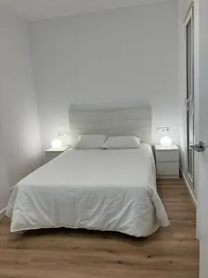 a white bedroom with a white bed and two lamps at Plus Ultra Ruzafa 6 in Valencia