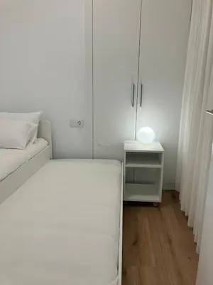 a white bedroom with a bed and a night stand at Plus Ultra Ruzafa 6 in Valencia