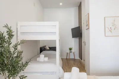 a white bedroom with a bunk bed and a couch at Flats Uruguay in Valencia