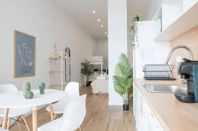 a white kitchen with a white table and white chairs at Flats Uruguay in Valencia