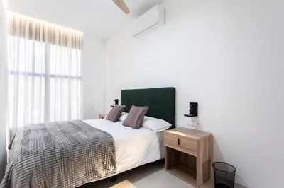 a white bedroom with a bed and a window at Aqua Suites Ciudad de las Artes I in Valencia