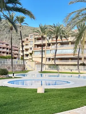 a swimming pool in front of a building with palm trees at Bahia Park Résidence in Cullera
