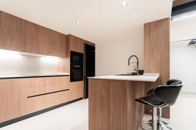 a kitchen with wooden cabinets and a black chair at Aqua Suites Ciudad de las Artes II in Valencia