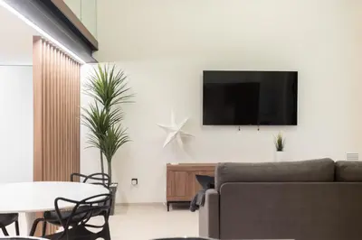 a living room with a couch and a tv on a wall at Aqua Suites Ciudad de las Artes II in Valencia