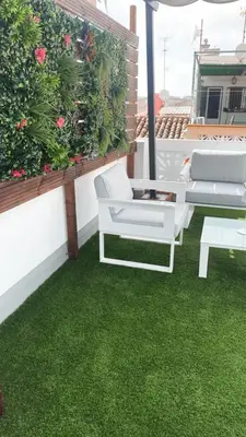 a patio with green grass and white chairs on a balcony at Stylish and renovated house in Cullera