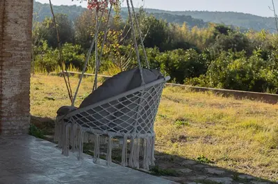 a swing hanging from a building with a field at Hort de les Oronetes in Alzira
