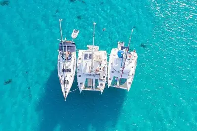 two boats are docked in the blue water at Barco para dormir sobre el Mar in Valencia