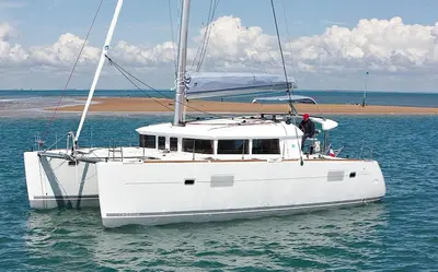 a white boat floating in the water near a beach at Catamaran Nora in Puebla de Farnals