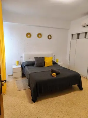 a bedroom with a bed with yellow sheets and two windows at Apartamento playa Valencia in Mareny Barraquetas
