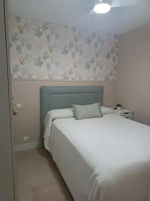 a bedroom with a white bed and floral wallpaper at Cullera Playa de los Olivos Apartment in Faro de Cullera