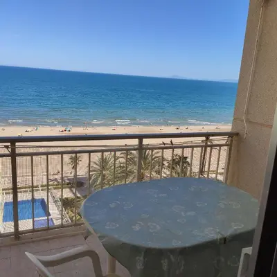 a table on a balcony with a view of the beach at Apartamento primera línea Cullera in Cullera