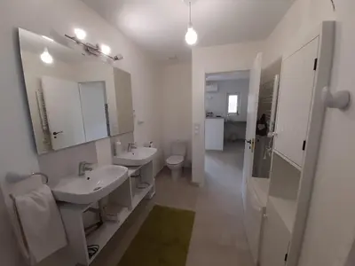 a white bathroom with two sinks and a toilet at Casa Kiosko 1 bedroom ground floor with swimming pool in La Eliana