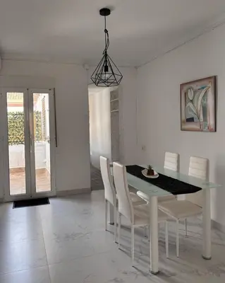 a dining room with a table and white chairs at A vacation by the sea in Puerto de Sagunto