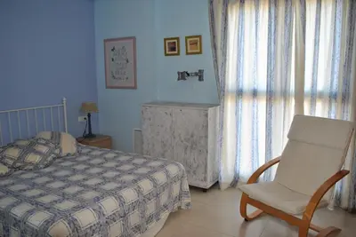 a bedroom with a bed and a chair and a window at RelaxUp Apartment Patacona Beach in Valencia