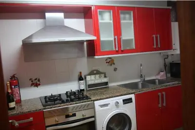 a kitchen with red cabinets and a washing machine at Puebla de Farnals playa- Oasis Apartments - Costa de Valencia Beachside Stay in Puebla de Farnals