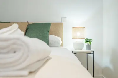 a bed with white sheets and green pillows at Flats poeta serrano in Valencia