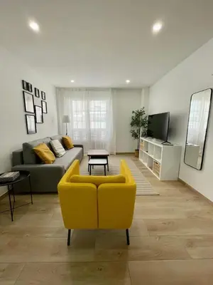 a living room with a yellow chair and a couch at White Lily in Godella