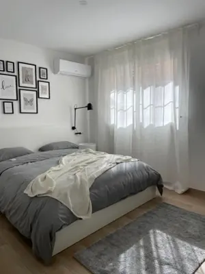 a white bedroom with a bed and a window at White Lily in Godella