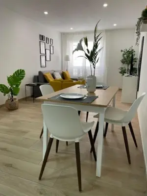 a dining room and living room with a table and chairs at White Lily in Godella