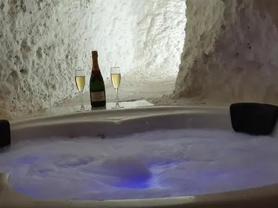 a bath tub with two wine glasses and a bottle of champagne at casa cueva a 15 minutos del centro de Valencia in Paterna