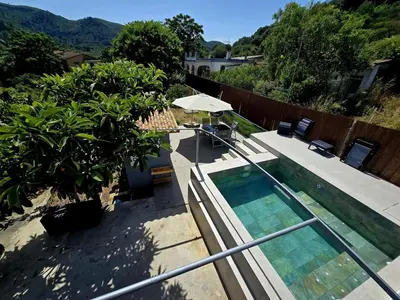 a swimming pool with an umbrella next to a house at Casa Rural El Bressol in Barraca de Aguas Vivas